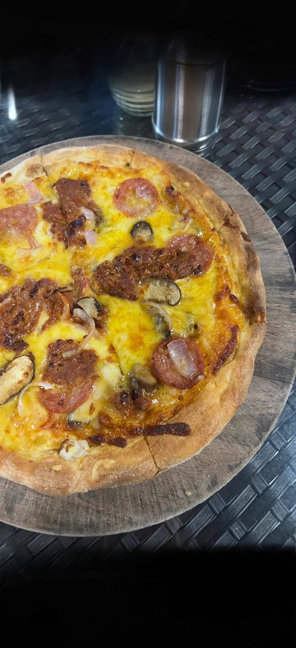 A sourdough pizza at ARFC with pepperoni, sausage, mushrooms and onion on a wooden board