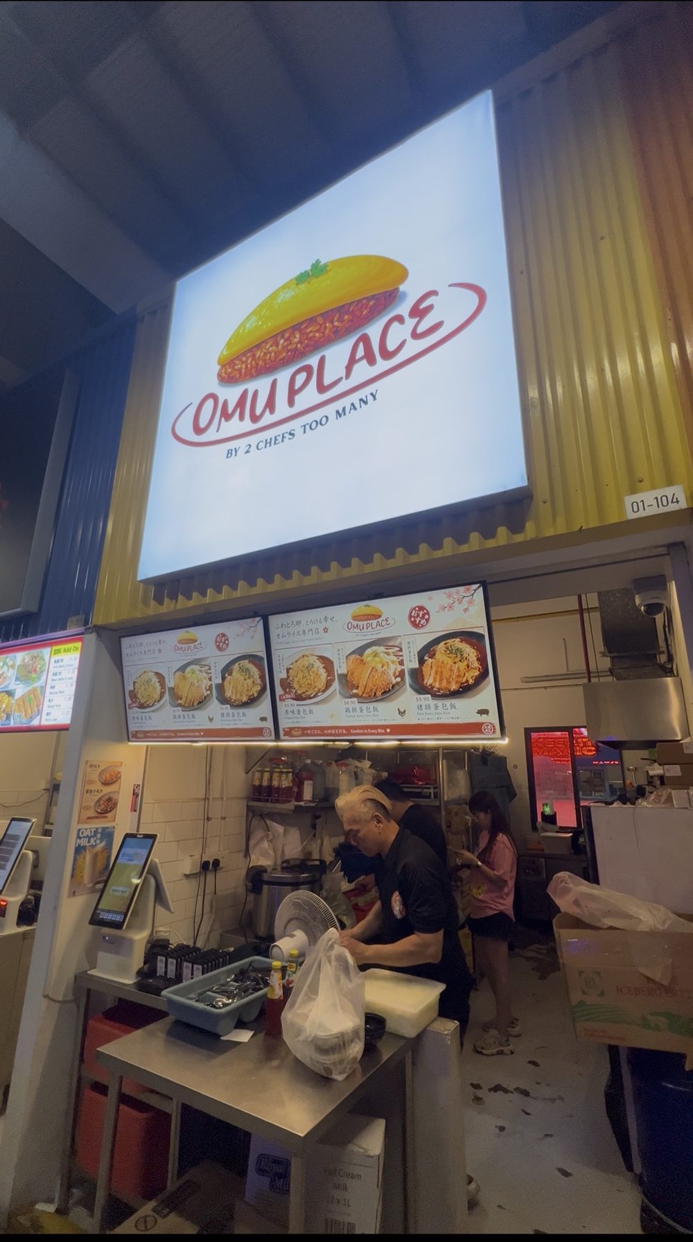Omu Place by 2 Chefs Too Many, stall #01-104, with its omurice menu board and a cook at work