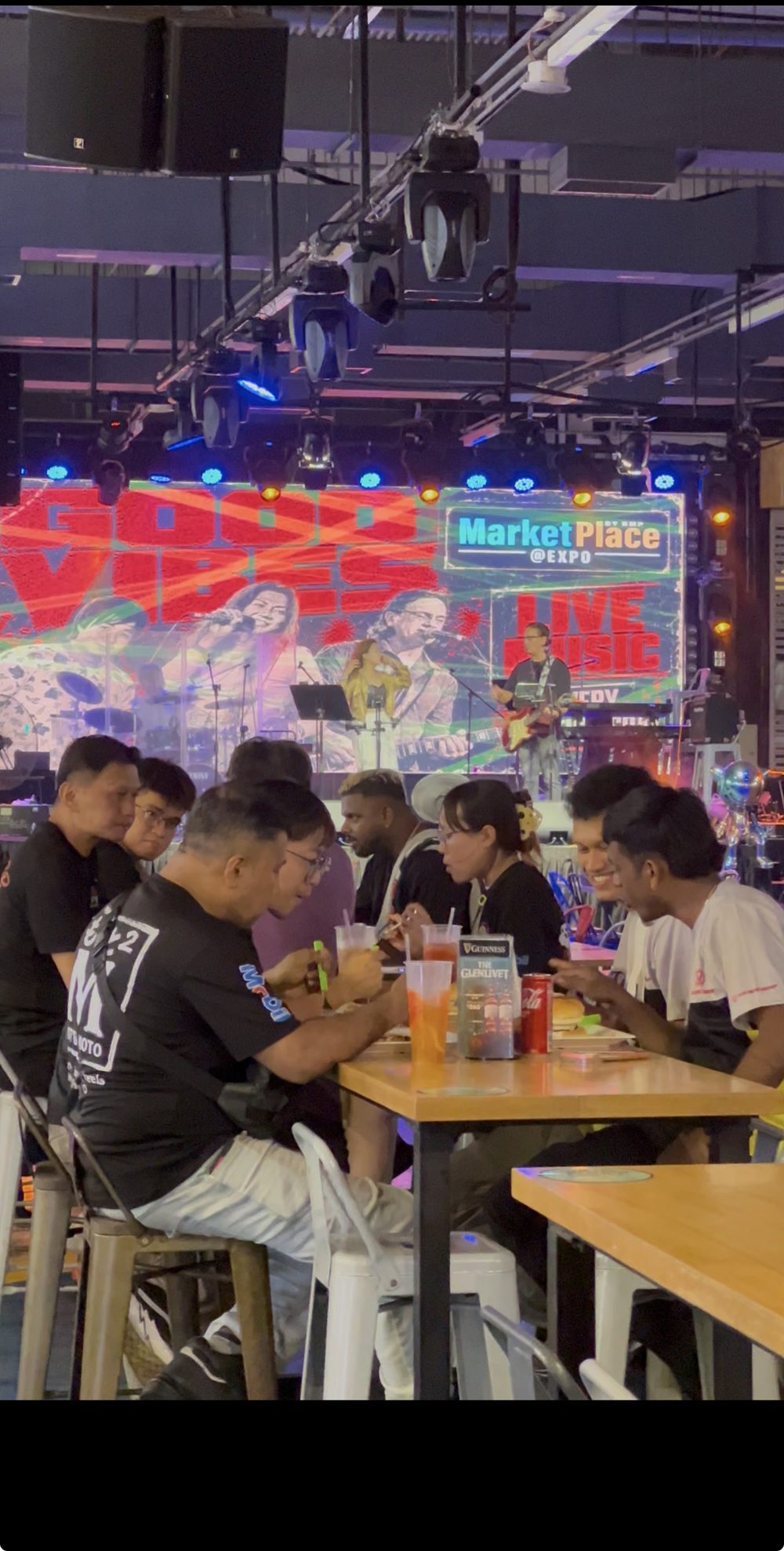 A live band on stage at MarketPlace @ Expo, with diners at the tables in front